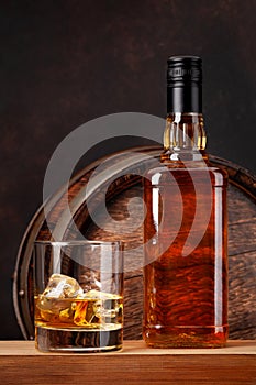 Scotch whiskey bottle, glass and old barrel