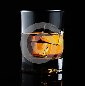 Scotch whiskey in an elegant glass with ice cubes on black background
