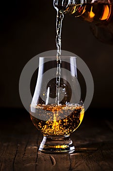 Scotch Whiskey without ice pouring out of the bottle, rustic wood background, copy space