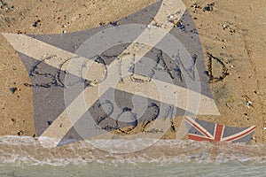 Scotland 2021 written in sand, Scottish flag up British flag flooded by water