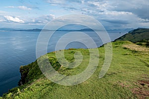 Scottish landscape with hills and shoreline near Staffin at Isle of Skye with green pastures for sheep