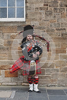 Scottish piper man dressing in Scottish traditional tartan kilt playing a bagpiper at Royal Mile in Edinburgh, Scotland, UK