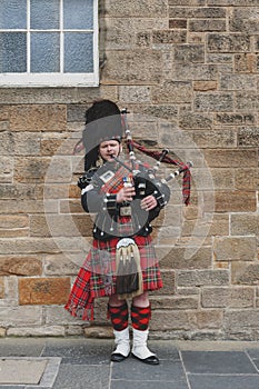 Scottish piper man dressing in Scottish traditional tartan kilt playing a bagpiper at Royal Mile in Edinburgh, Scotland, UK