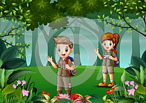 Scout boy and girl in uniform exploring the forest