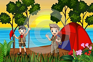 The scout boys camping by the lake at sunset