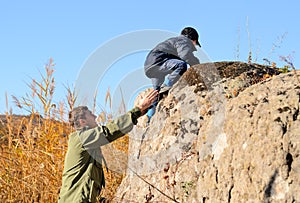 Scout helping a young boy rock climbing