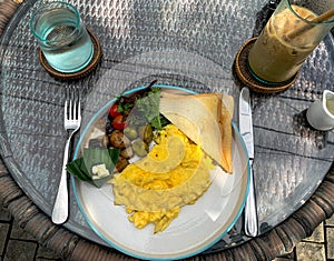 Scrambled egg breakfast with grilled vegetables, toast, and iced