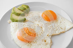 Scrambled eggs with avocado and specialy on a white plate on a white background. Close-up, top view