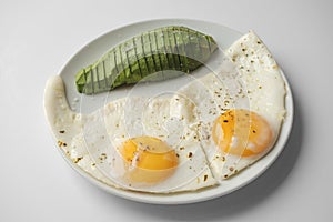 Scrambled eggs with avocado and specialy on a white plate on a white background. Close-up, top view