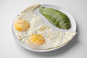 Scrambled eggs with avocado and specialy on a white plate on a white background. Close-up, top view