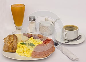 Scrambled eggs, basil, papaya juice, coffee, ham, fried bacon, bread.