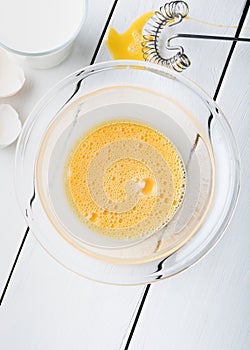 Scrambled eggs in a glass bowl with glass of milk.