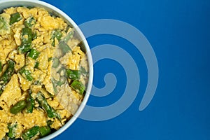 Scrambled eggs with green asparagus, a traditional Alentejo dish, set against a blue backdrop