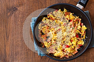 Scrambled eggs with ham, vegetables and cheese in a frying pan