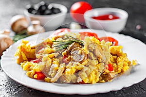 Scrambled eggs with mushrooms and vegetables in white plate