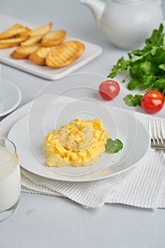 Scrambled eggs, omelet, vertical. Breakfast with pan-fried eggs, glass of milk, tomatoes on white background