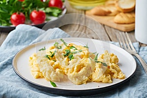 Scrambled eggs, omelette, close up. Breakfast with pan-fried eggs, cup of tea, tomatoes on old wooden table