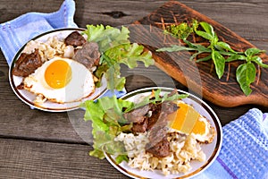 Scrambled eggs, pasta and beef steak, top view, vintage rustic style