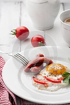 Scrambled eggs on a plate with pieces of tomato and sausage