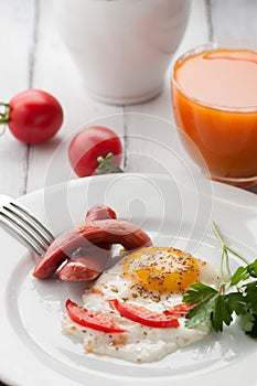 Scrambled eggs on a plate with pieces of tomato and sausage