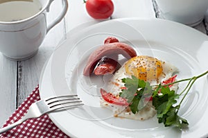 Scrambled eggs on a plate with pieces of tomato and sausage