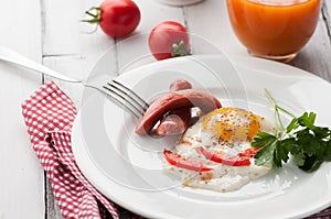 Scrambled eggs on a plate with pieces of tomato and sausage