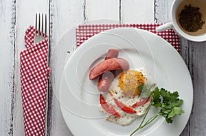 Scrambled eggs on a plate with pieces of tomato and sausage