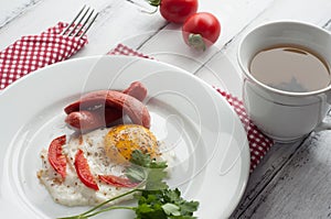 Scrambled eggs on a plate with pieces of tomato and sausage