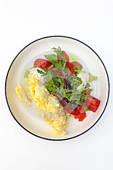 Scrambled eggs on a plate with tomatoes and herbs. Healthy breakfast. Vegetarian menu. The concept of healthy eating