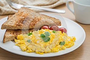 Scrambled eggs and toast on a plate and coffee cup