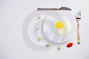 Scrambled eggs on a white plate and a bright white table