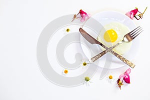 Scrambled eggs on a white plate and a bright white table