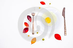 Scrambled eggs on a white plate and a bright white table