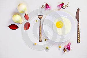 Scrambled eggs on a white plate and a bright white table