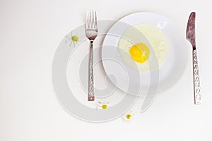 Scrambled eggs on a white plate and a bright white table