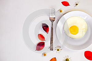 Scrambled eggs on a white plate and a bright white table