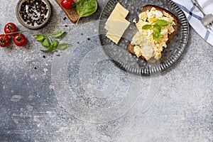 Scrambled eggs on whole grain bread on a stone table. Homemade breakfast or brunch meal - scrambled eggs. View from above. Copy