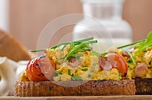Scrambled eggs witch bacon, herbs and tomato
