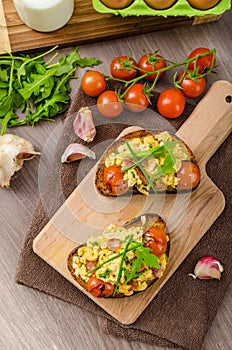 Scrambled eggs witch bacon, herbs and tomato