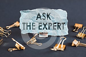 A scrap of blue paper with clips on a gray background with the text - ASK THE EXPERT