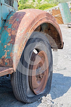 A scrap car wheel, a rusted, sweaty vehicle