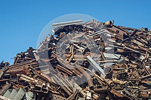 Scrap heap of rusty steel, aluminium under blue sky prepared to be recycled