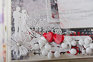 Scrapbooking photo album page with paper decorative elements, flowers, hearts, ribbons, beads. Just married couple paper shapes