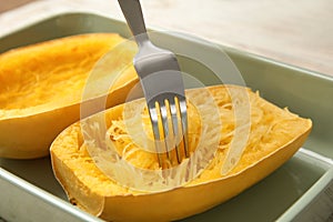 Scraping flesh of cooked spaghetti squash with fork