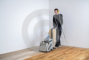 Carpenter doing parquet wood floor polishing maintenance work by machine photo