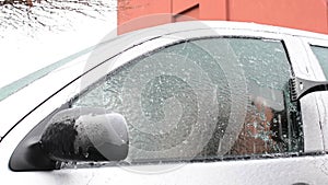 Scrapping ice glazed car windows after blizzard