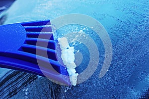 Scrapping ice of the windshield near car wiper, after a cold winter night