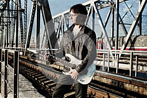 Scratch effect on photo men with guitar on a railroad