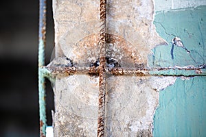 Scratched and broken down painted cement wall with rusty reinforcement and old color ragged plaster wall texture