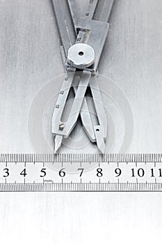 scratched metal background with proportional divider and standard ruler on it